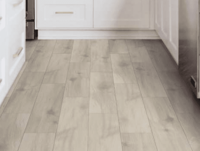 A kitchen with white cabinets and wood floors.