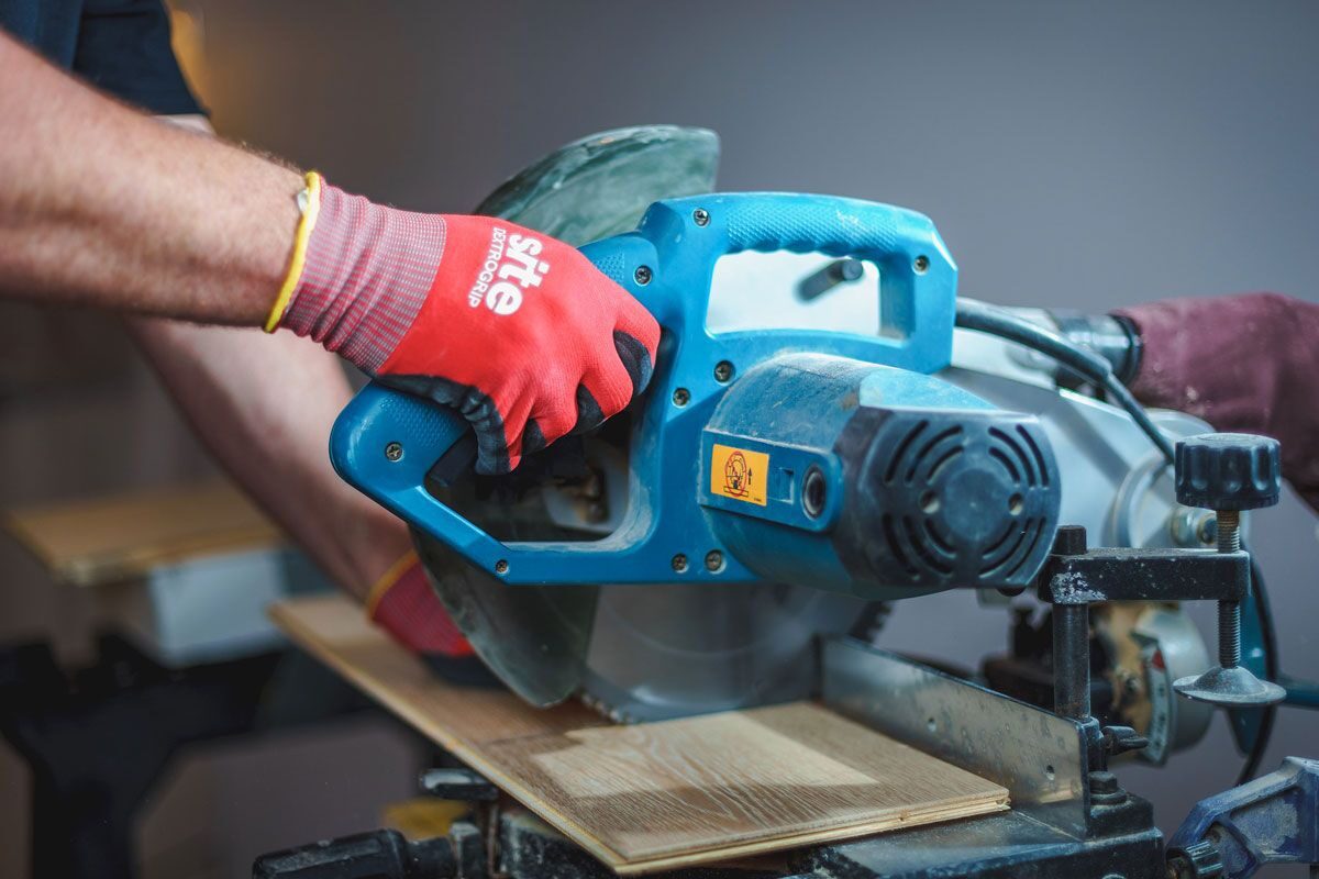 A person using a miter saw on a table.