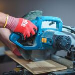 A person using a miter saw on a table.