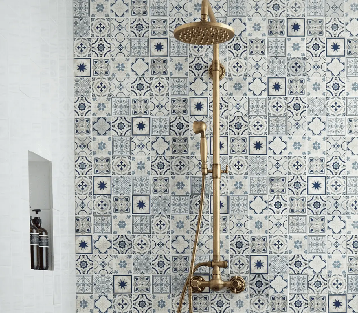 A shower with a gold faucet and a blue tile wall.