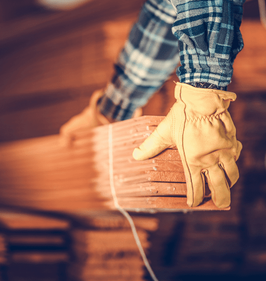 A person holding onto some wood in a warehouse.