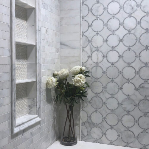 A vase of flowers in the corner of a bathroom.