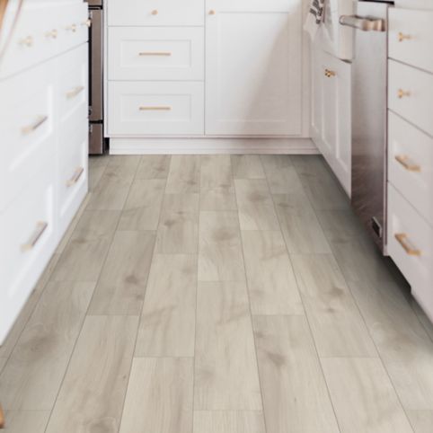 A kitchen with white cabinets and wood floors.