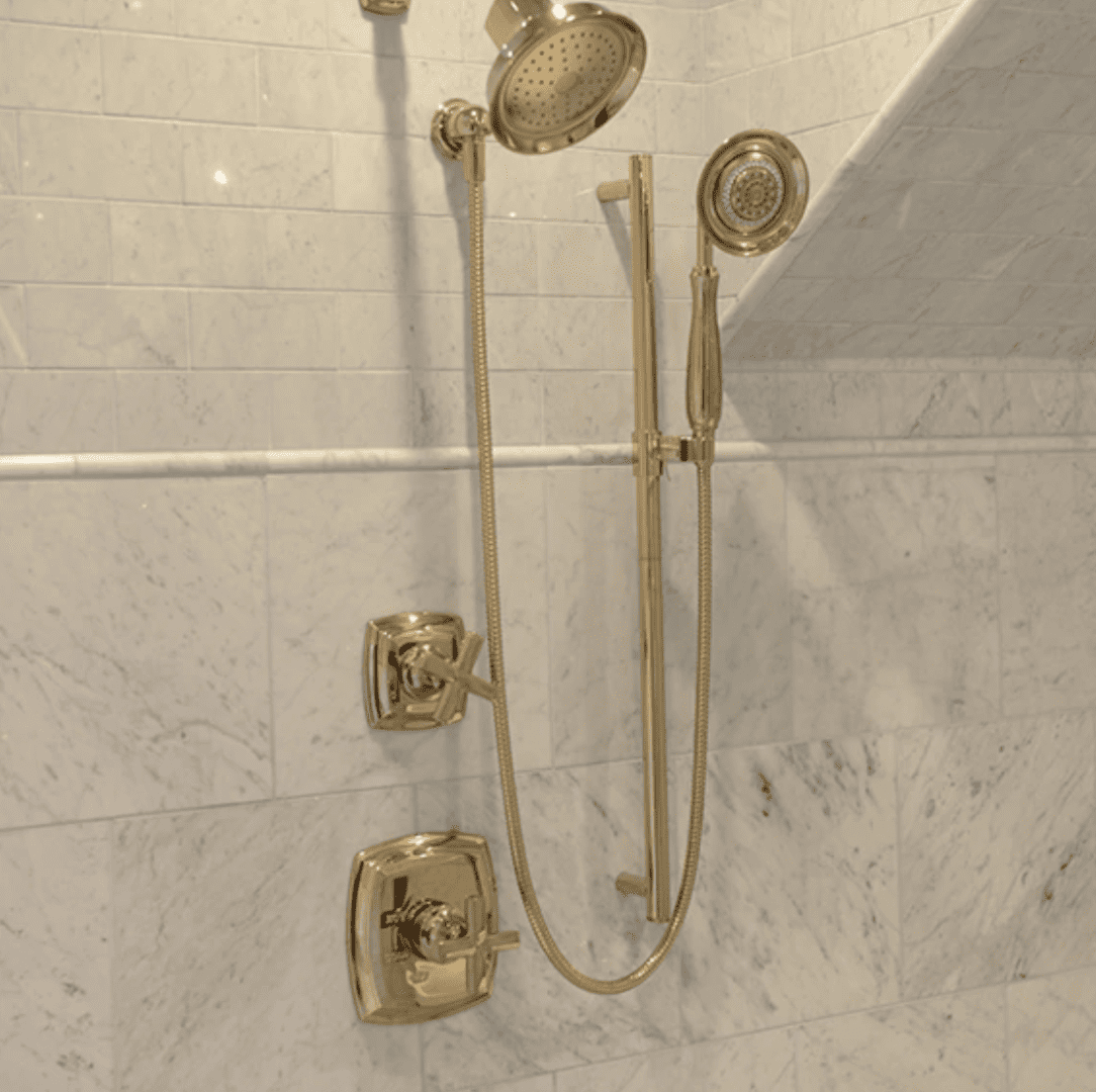 A shower head and hand held showerhead in the corner of a bathroom.