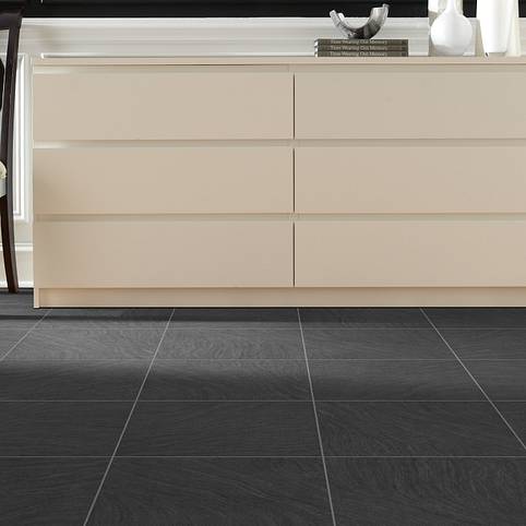 A white dresser and sink in front of a black tile floor.